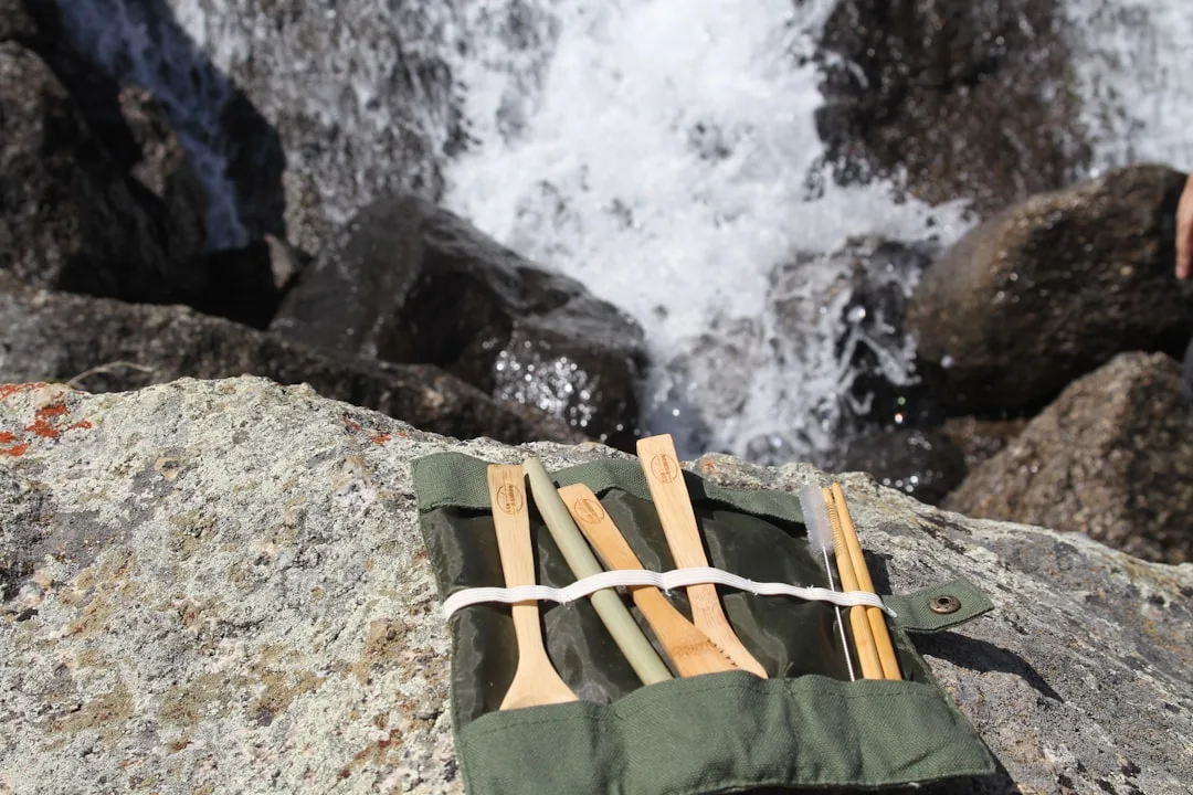 Bamboo toothbrushes in canvas roll on rocks beside a waterfall – zero-waste travel essentials
