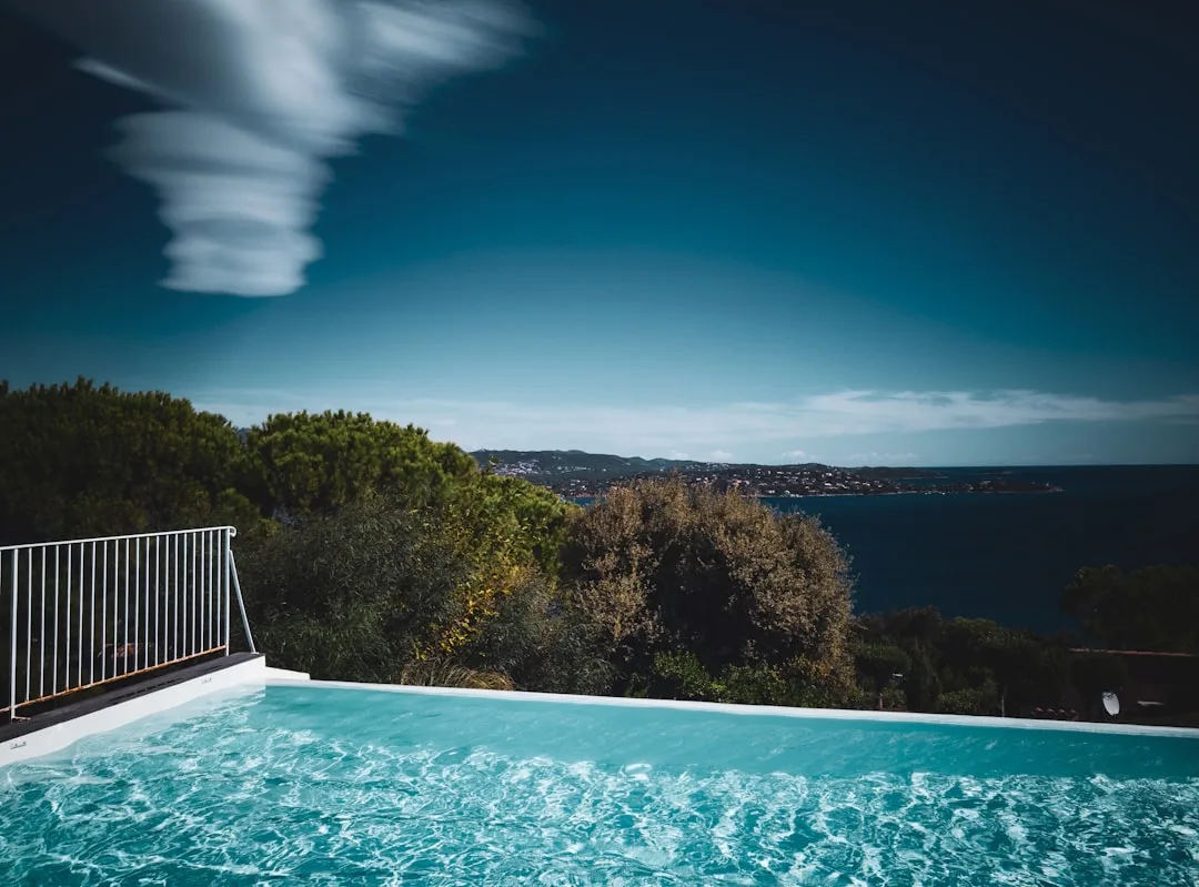 Infinity pool with panoramic ocean landscape view under blue sky