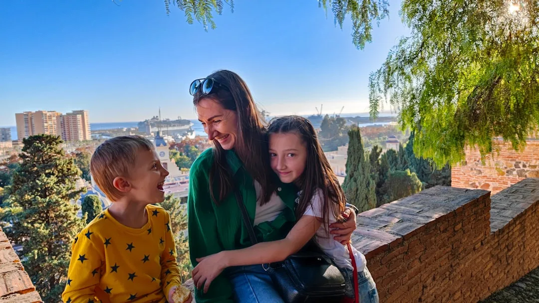 Mutter mit zwei Kindern auf einer Aussichtsterrasse mit europäischem Stadtpanorama