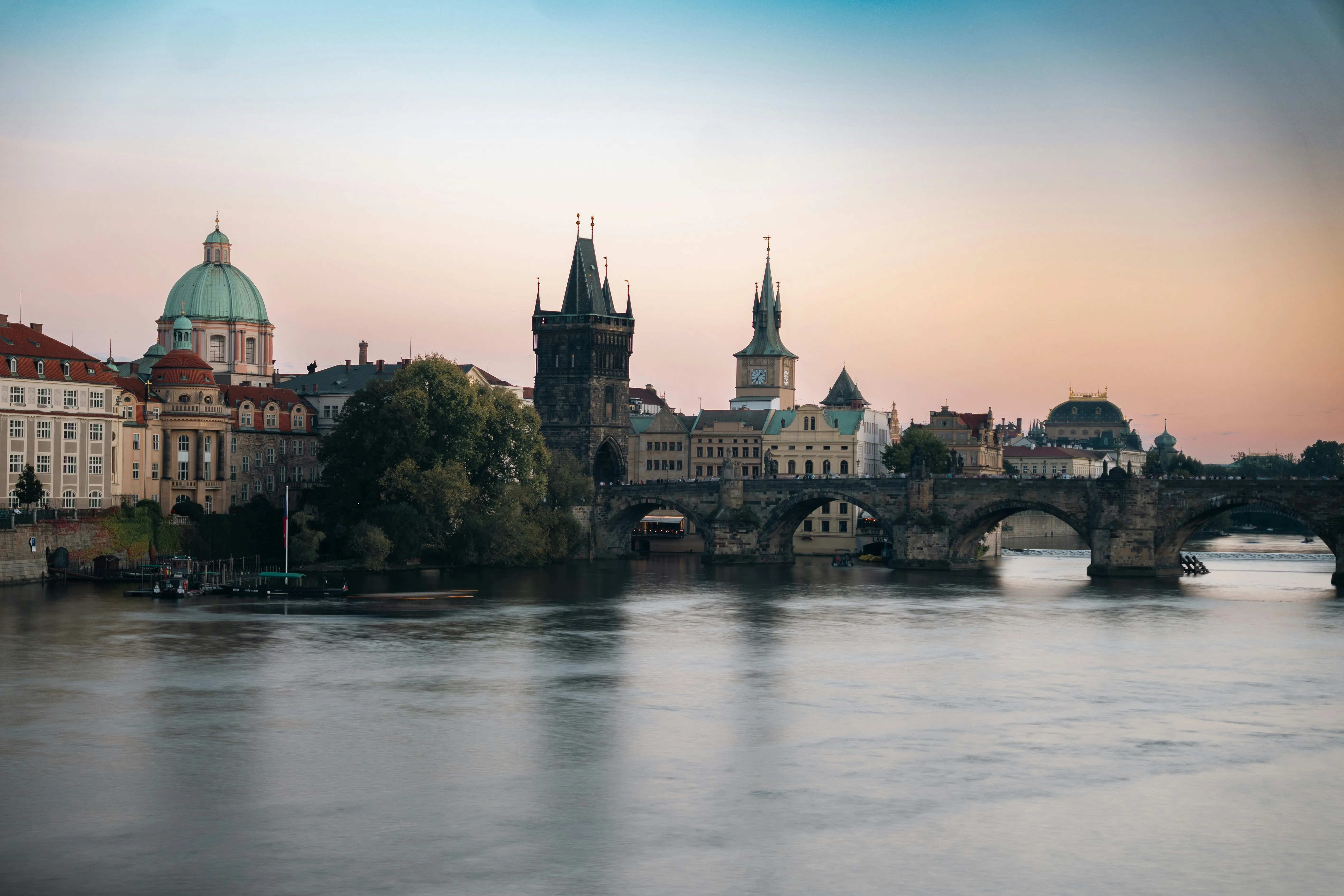 Charles Bridge in Prague at golden hour with Old Town skyline reflected on the Vltava River