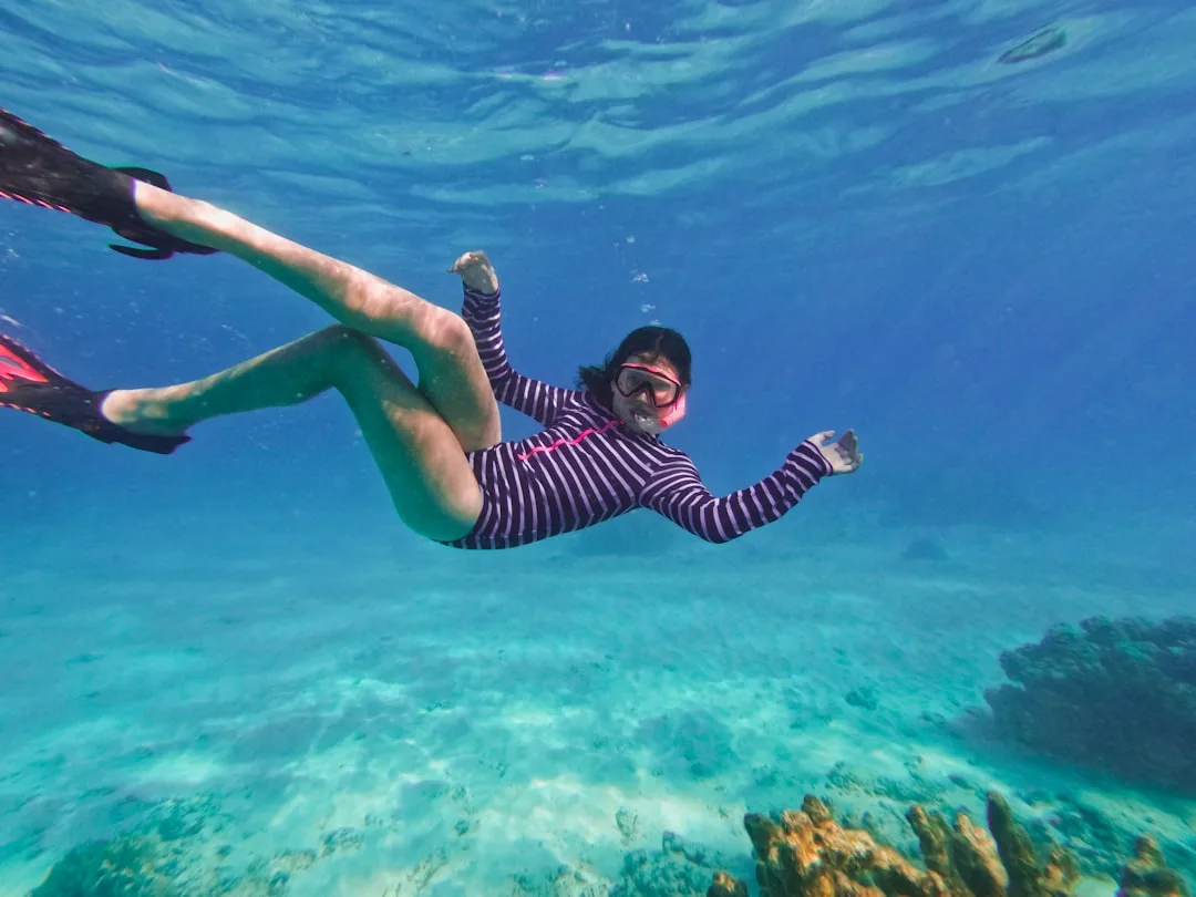 Woman snorkeling above colorful coral reef in clear turquoise sea water