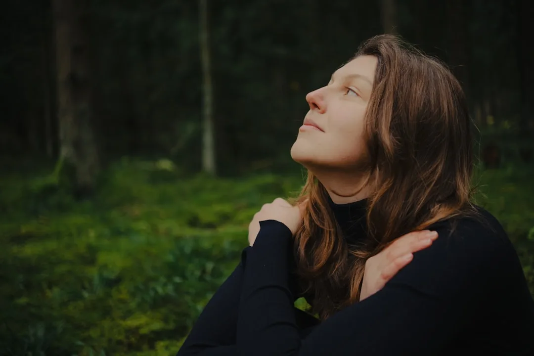Frau mit geschlossenen Augen geniesst Stille im Wald