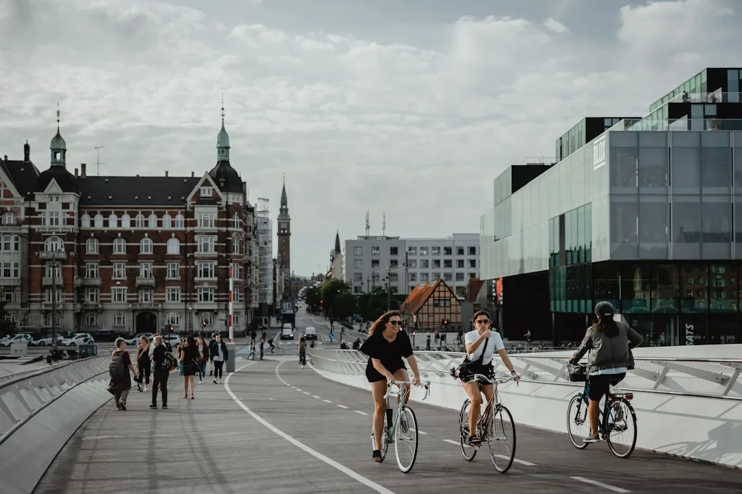 Two cyclists on a Copenhagen bridge against a historic city backdrop – sustainable urban tourism