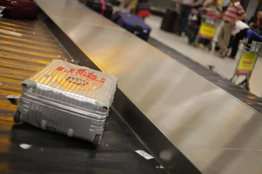 Gray hard-shell suitcase with priority tag on airport baggage claim belt