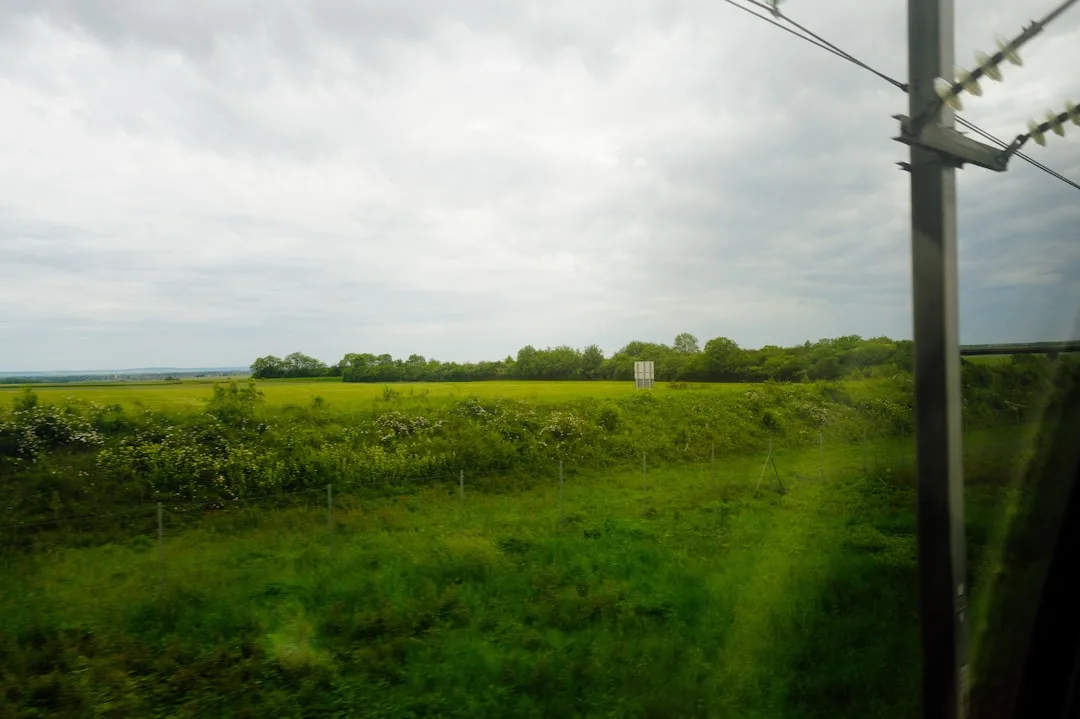 Weite grüne Landschaft mit sanften Hügeln und bewölktem Himmel — Slow Travel und Entschleunigung