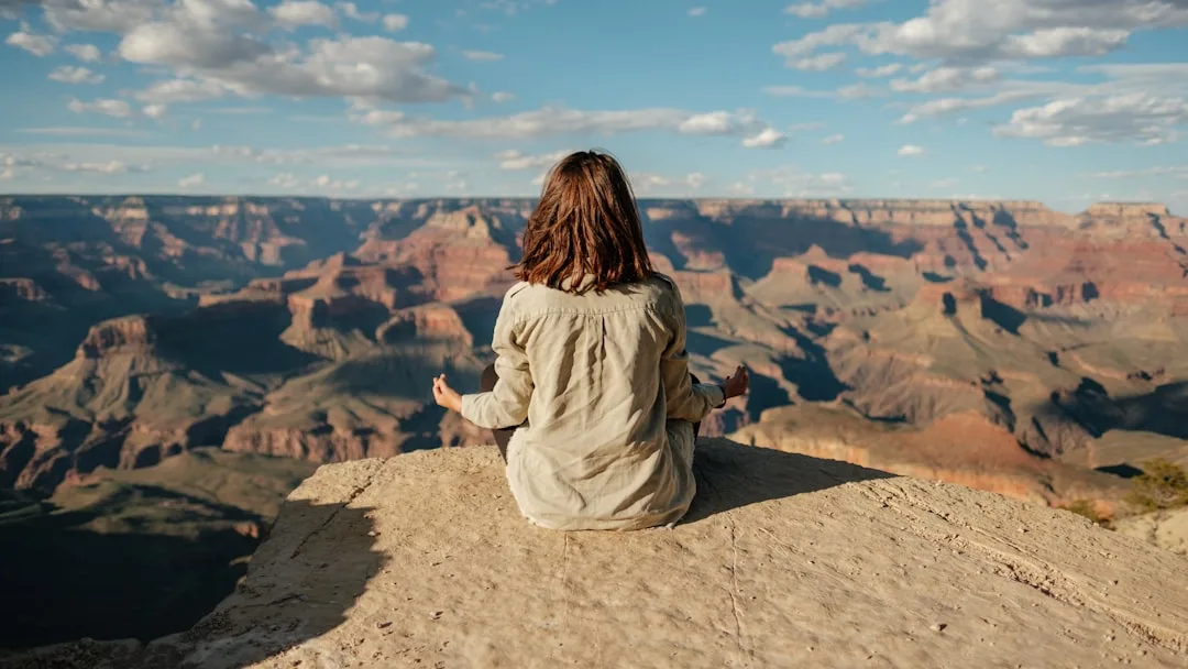 Frau sitzt in Stille am Rand des Grand Canyon und blickt in die weite Schlucht
