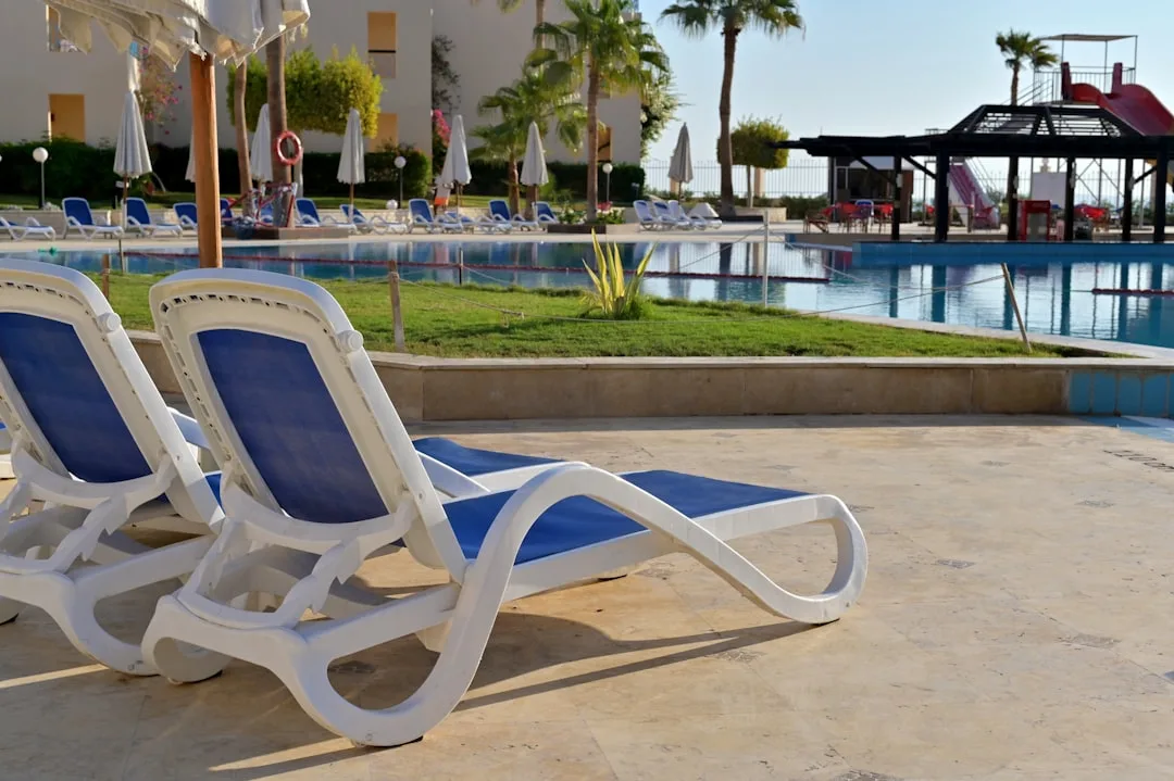 Blaue Strandliegen am Hotelpool mit weißen Sonnenschirmen an einem sonnigen Urlaubstag