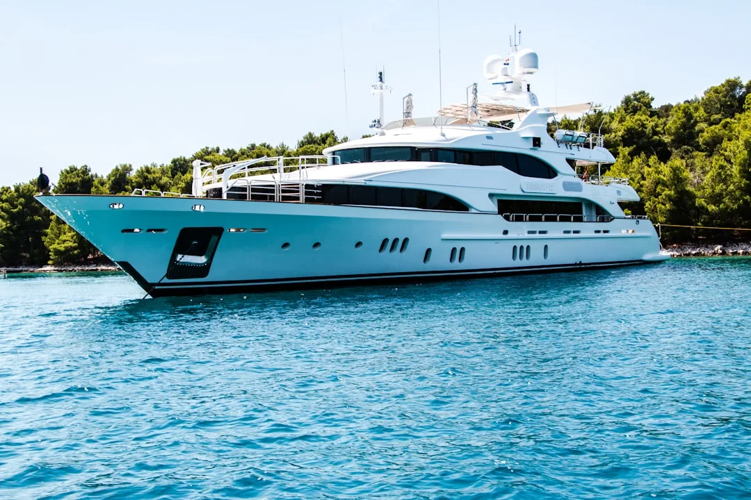 White luxury motor yacht on turquoise water with green coastline