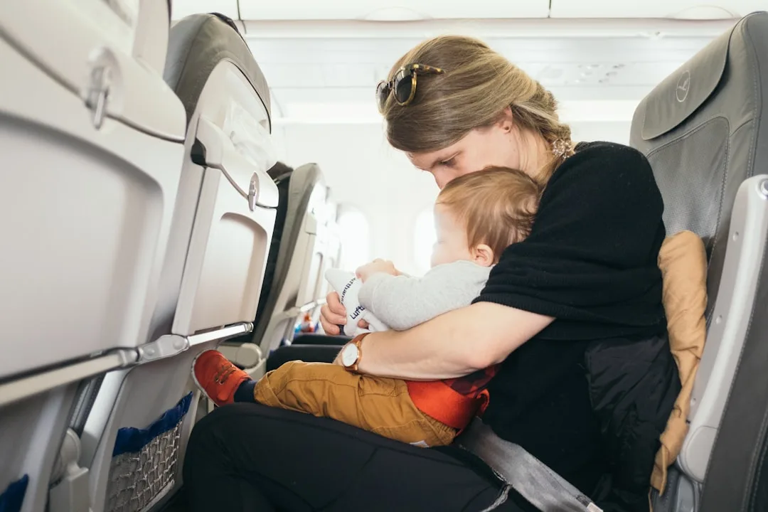 Mother holding sleeping baby on airplane seat after a long-haul flight