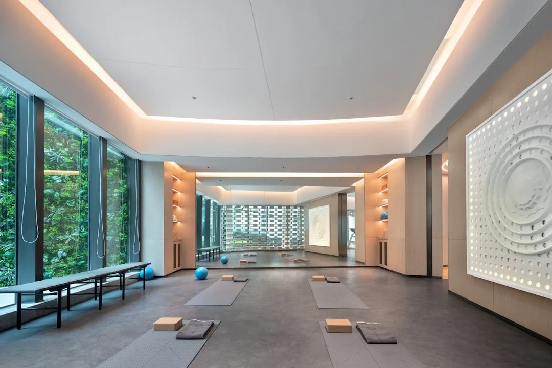 Modern yoga studio in a wellness hotel with floor-to-ceiling windows, yoga mats on the floor and a decorative mandala wall
